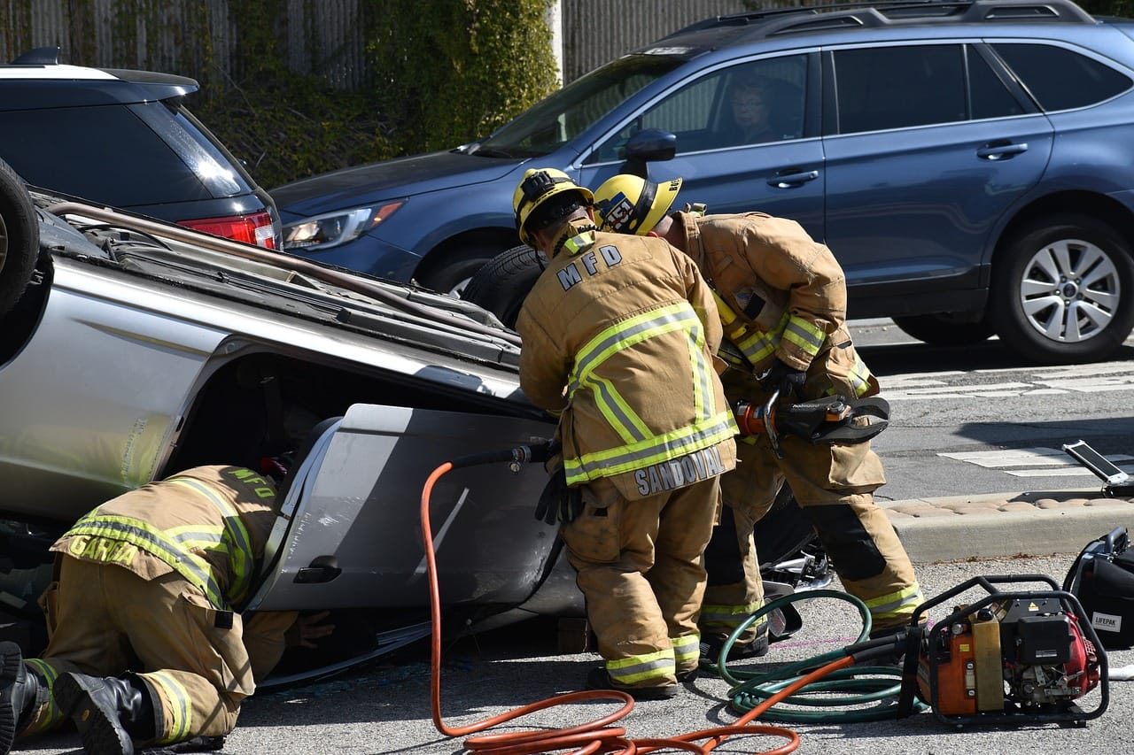 Careless Driving 4 Firefighters using hydraulic rescue tools to extricate a person from an overturned SUV after a careless driving collision